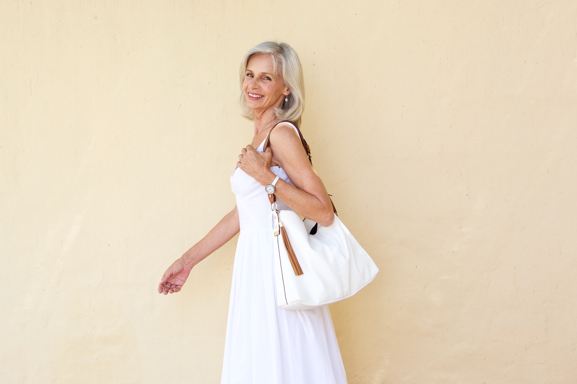 happy older woman in summer dress walking with purse